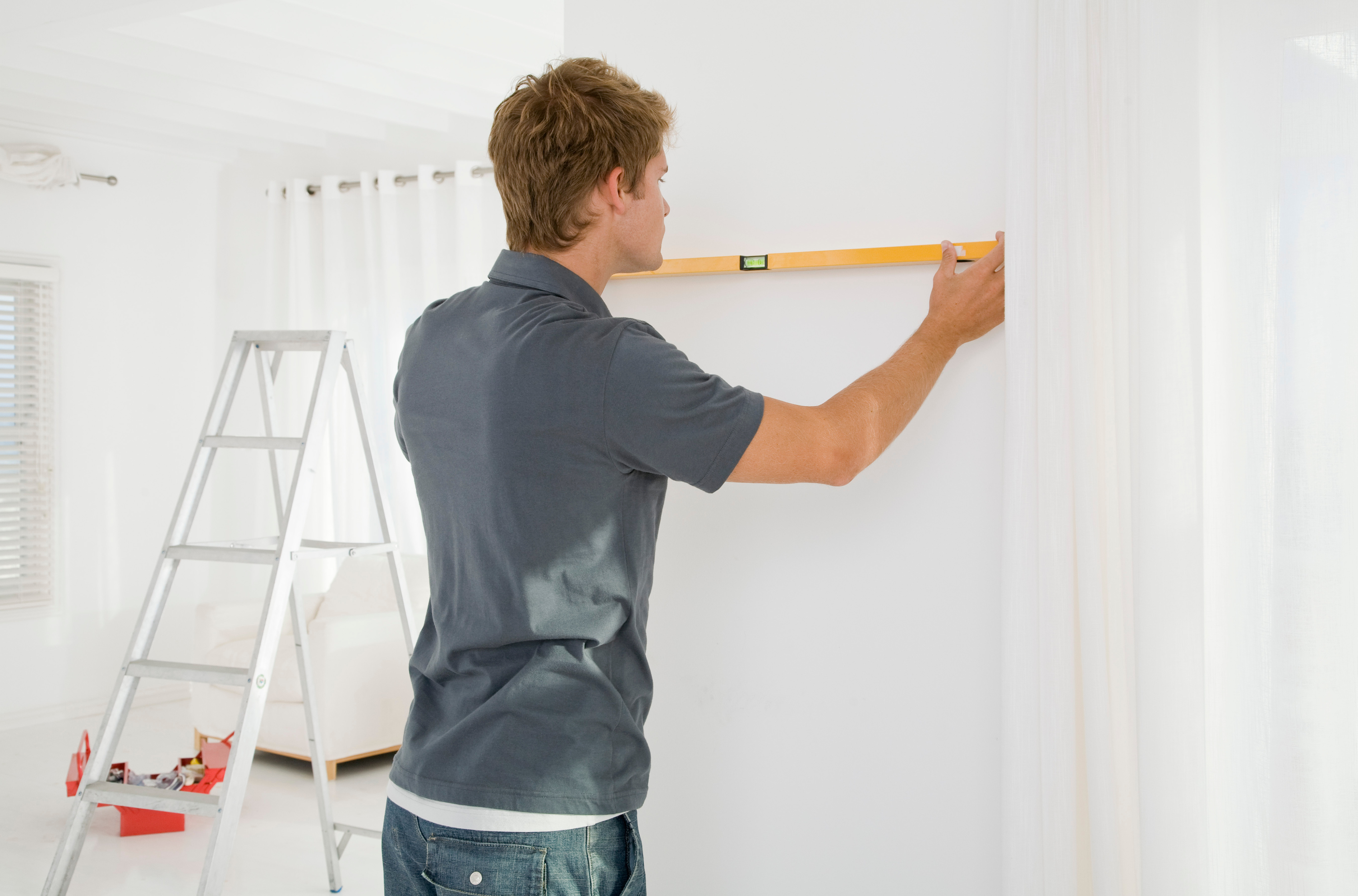 Man holding level against wall