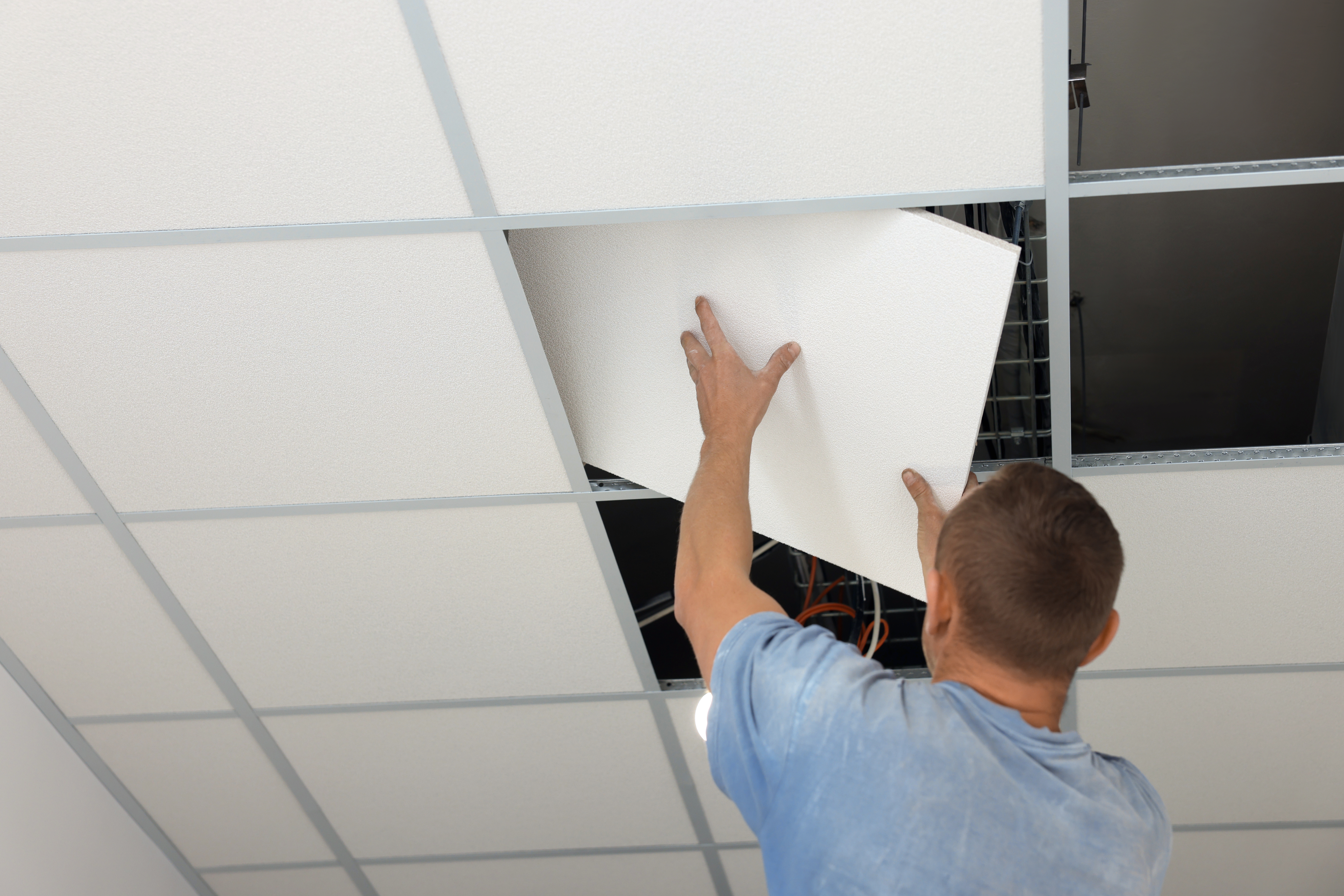 Suspended Ceiling Installation. Builder Working with PVC Tile, L
